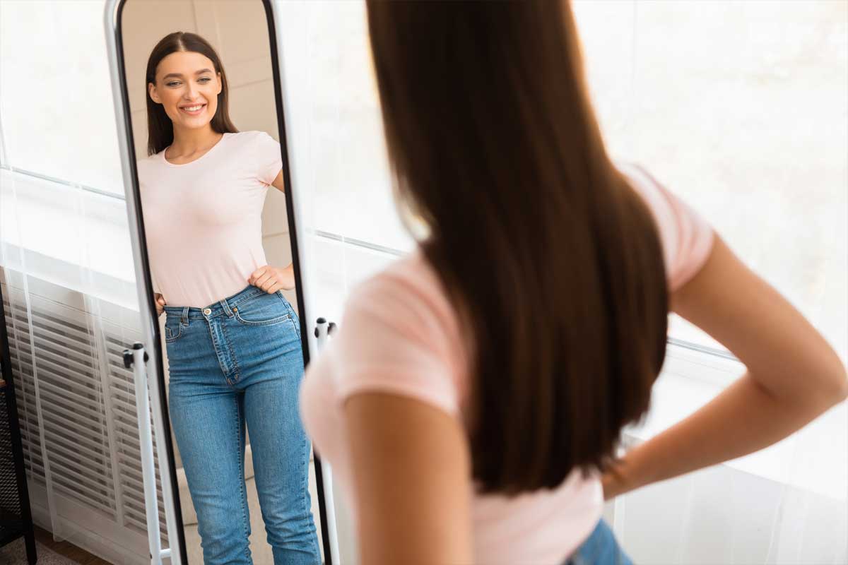 Štíhlá žena při pohledu do zrcadla